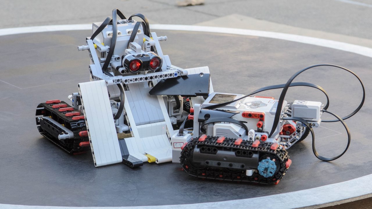two battle robots charge towards each other on a black circular arena