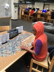Student working on jigsaw puzzle in library